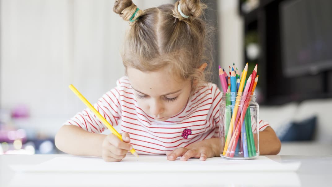 Mädchen zeichnet mit Buntstiften.