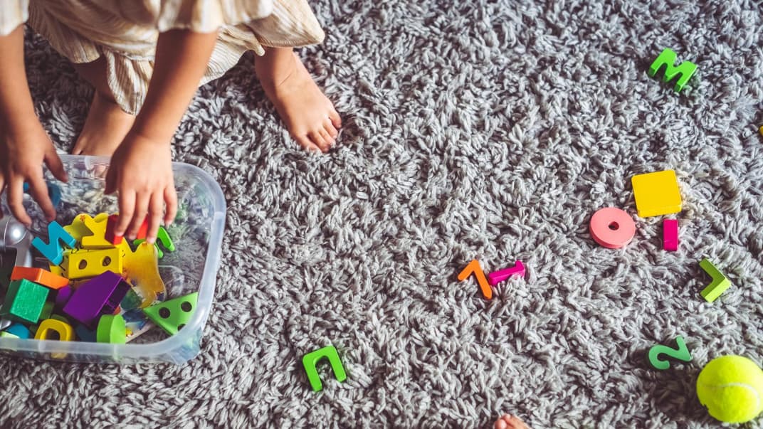 Kind räumt Spielsachen auf.