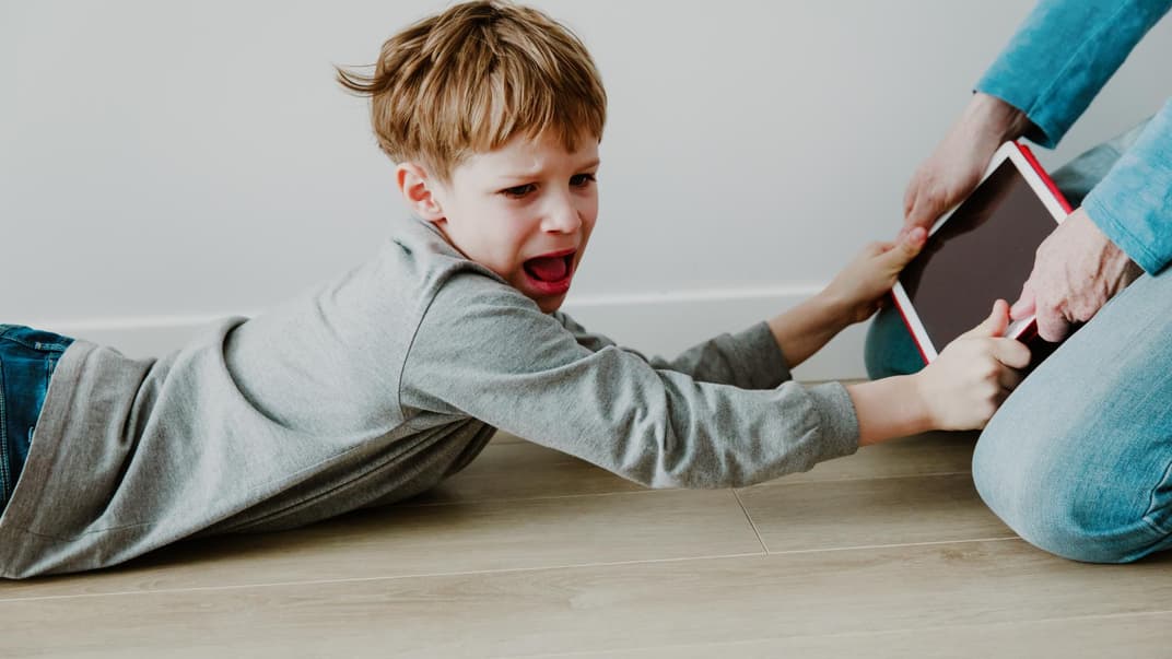 Junge hält schreiend das Tablet fest.