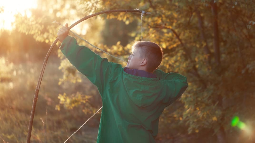 Junge mit Holzbogen und Pfeil