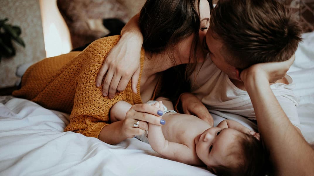 Eltern kuscheln mit Neugeborenem.