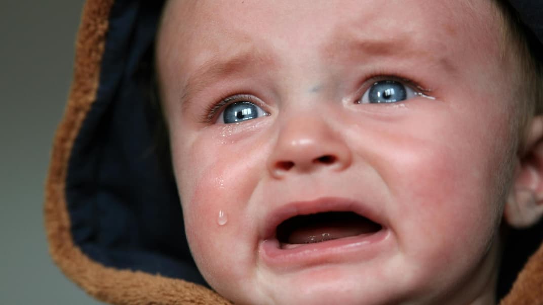 Weinendes Baby mit Kapuze.
