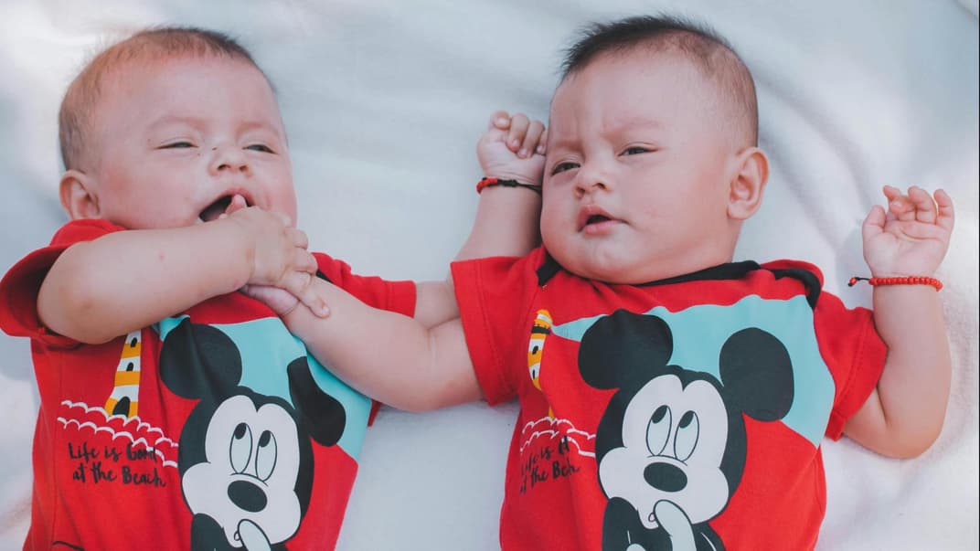 Zwillingsbabys mit Micky-Maus-Body
