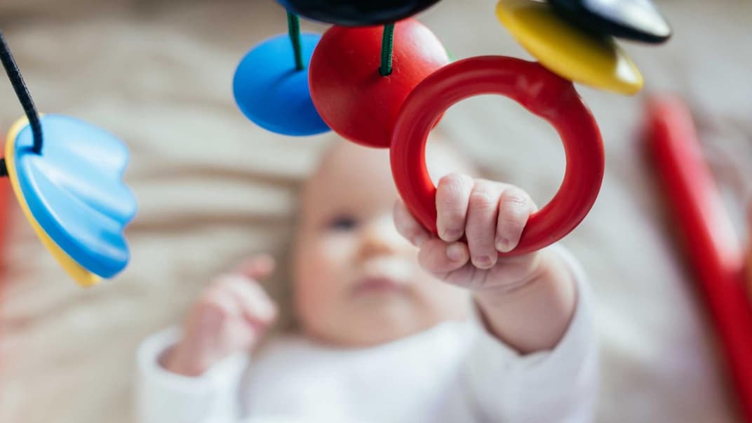 Baby greift nach einem Mobile.
