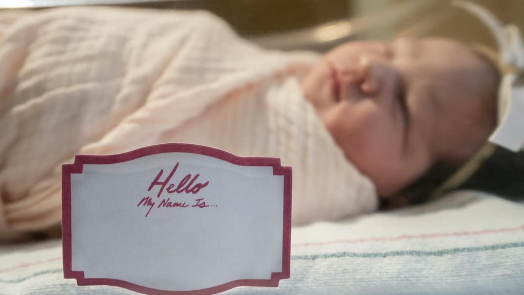 Ein Neugeborenes, vor dem ein Namensschild steht, das noch unbeschriftet ist.