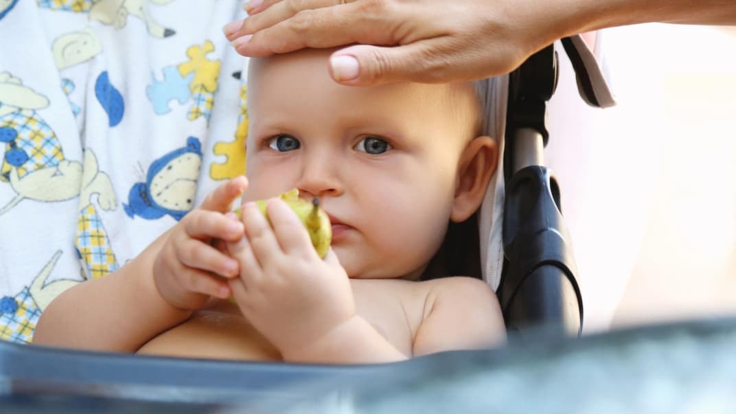 Eine Mutter fühlt die Stirn ihres Babys.