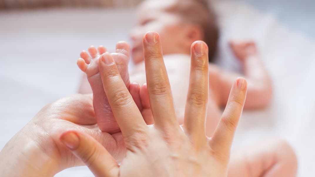 Mutter gibt Öl auf Babyfuß.