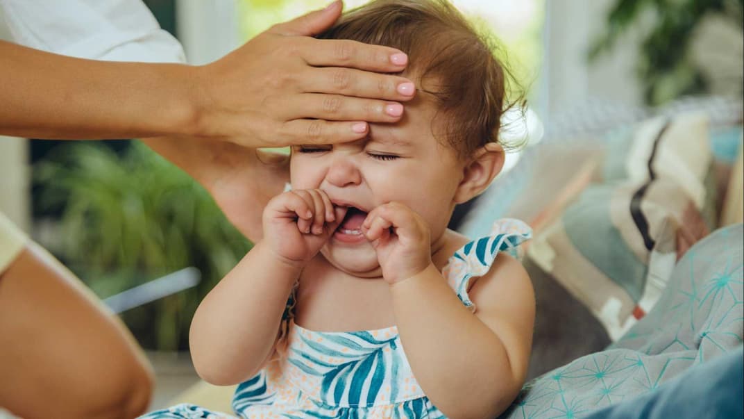 Mutter fühlt heiße Stirn eines schreienden Babys.