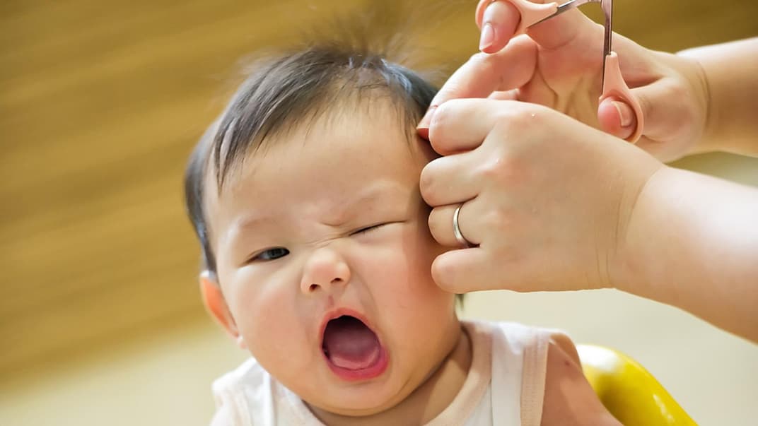 Babys sind nicht immer begeistert, wenn man ihnen die Haare schneiden möchte.