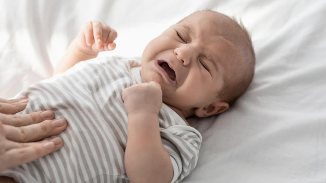 Weinendes Baby, dessen Bäuchlein massiert wird.