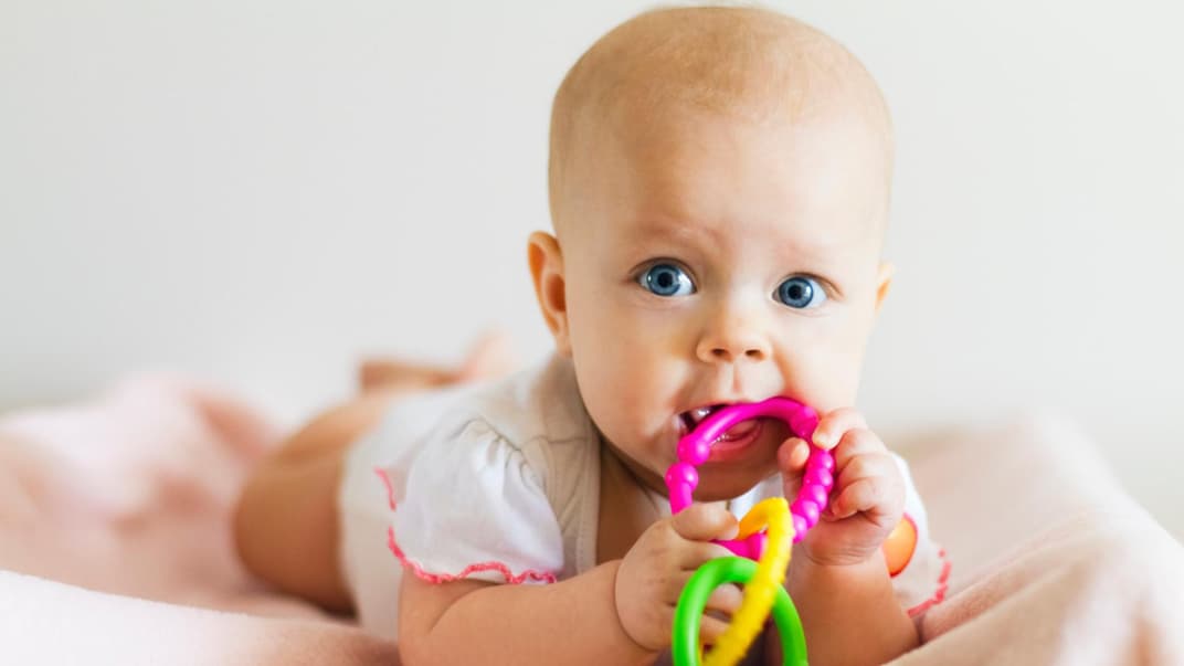 Baby liegt auf dem Bauch und kaum am Beißring.