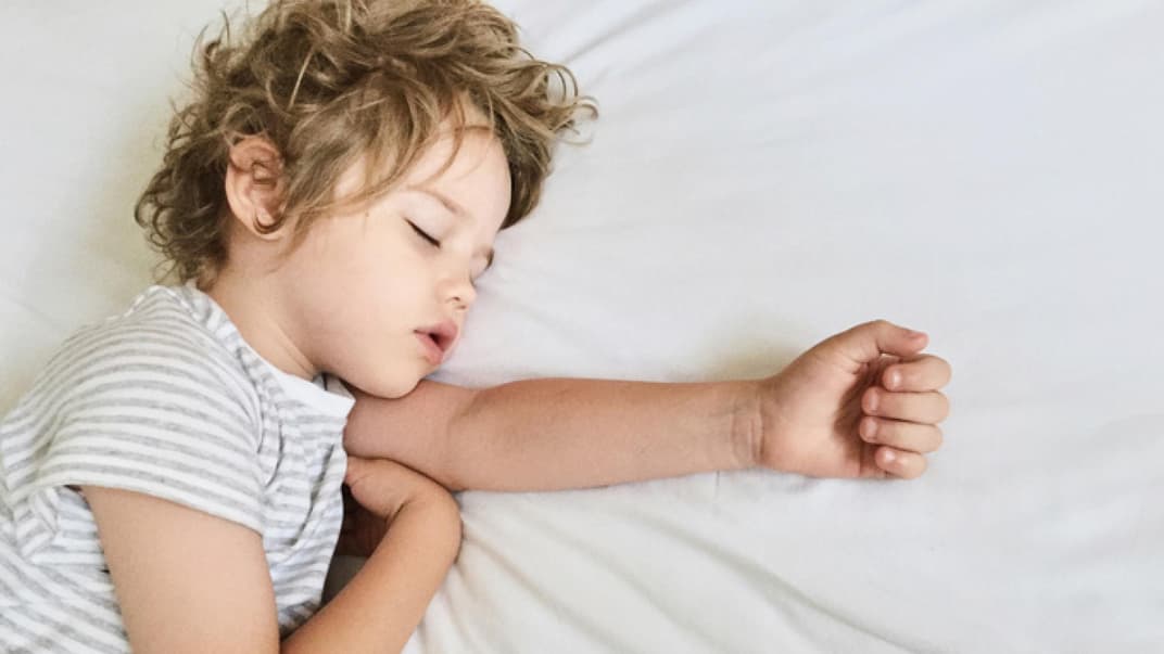 Kleines Kind schläft im Bett.