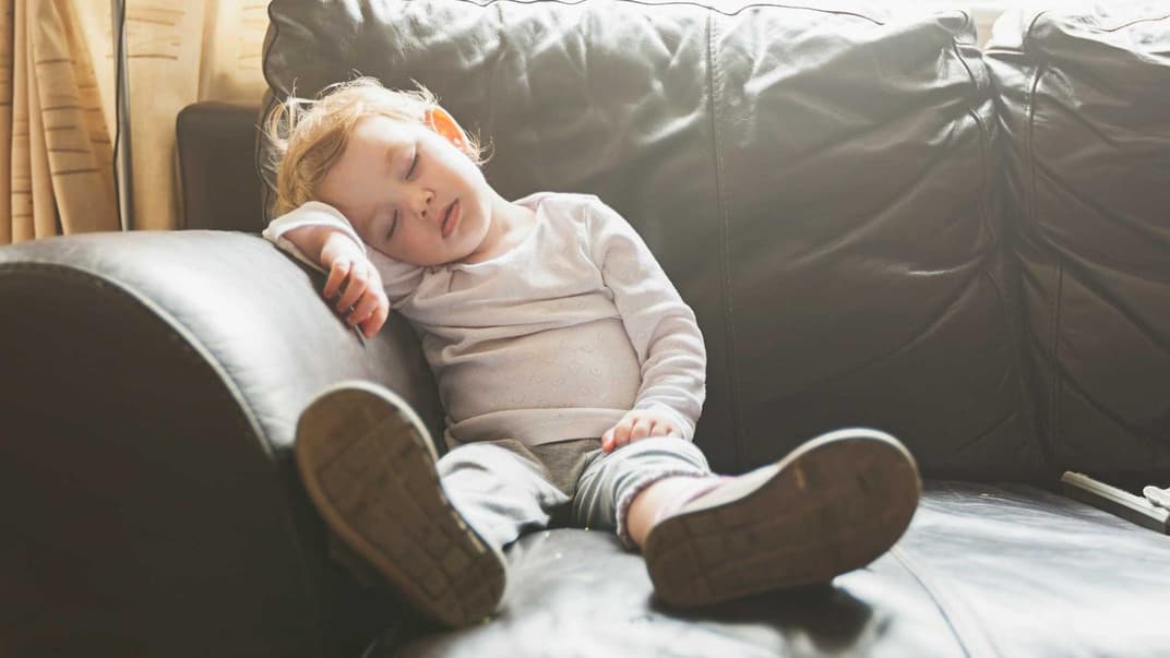 Ein Kleinkind, das auf dem Sofa einschläft.