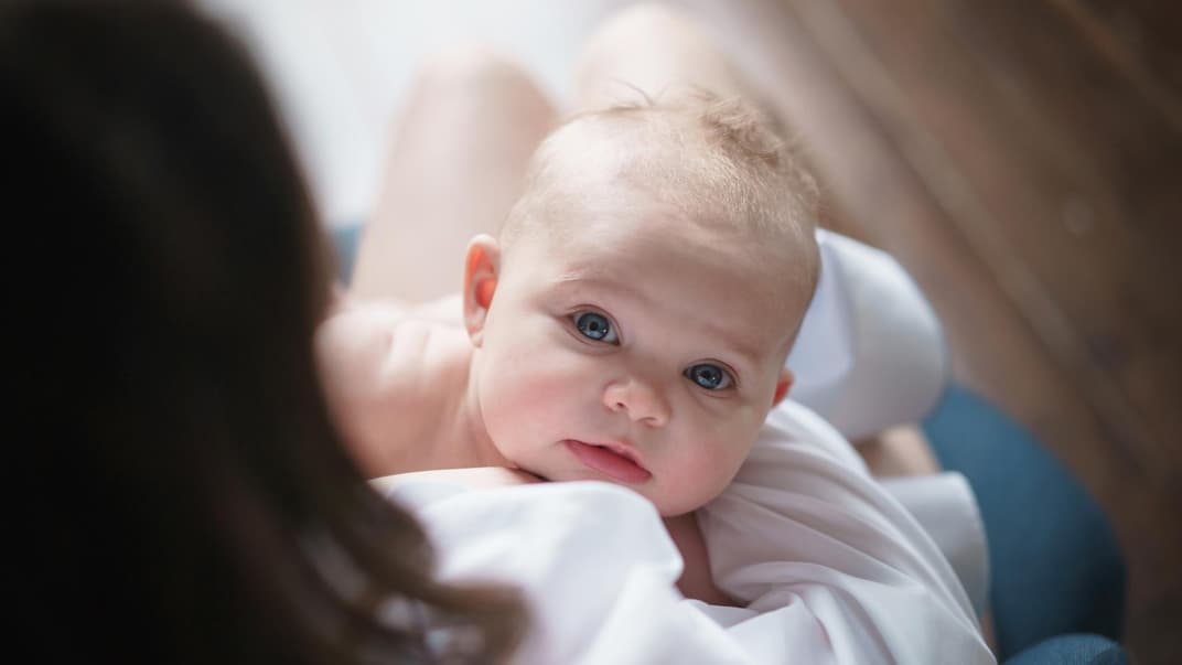 Kleines Baby schaut nach dem Stillen hoch.