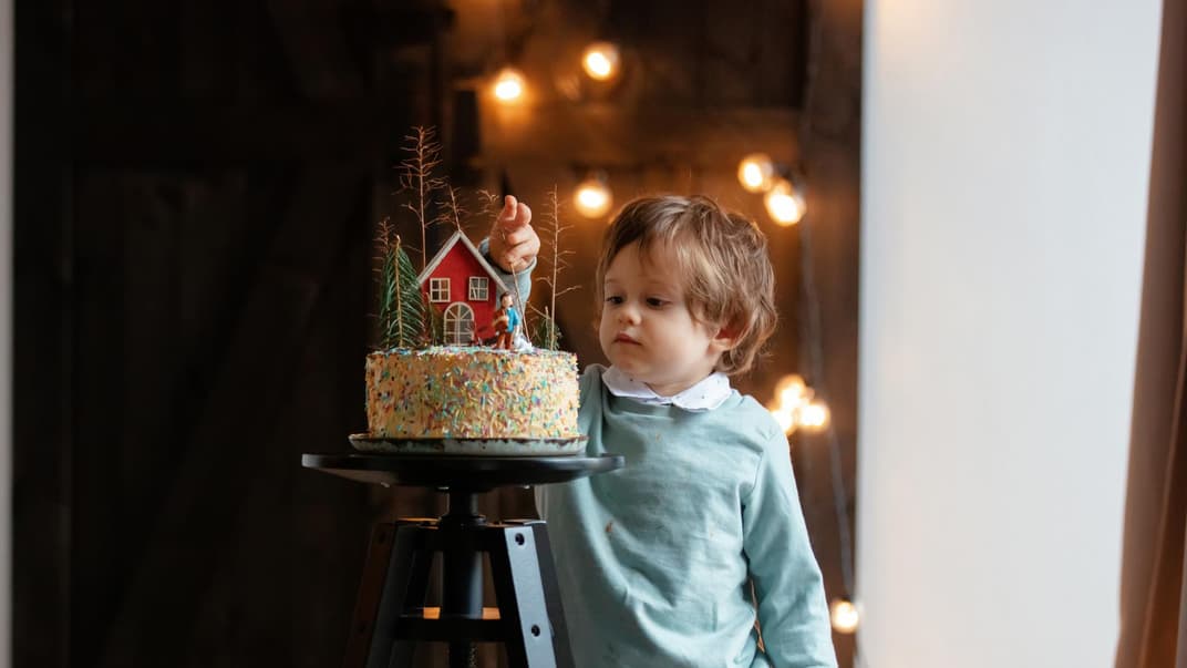 Ein kleiner Junge steht vor einer Torte. 