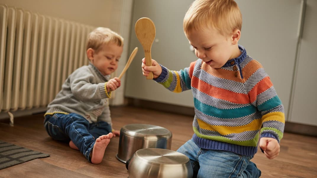 Kinder schlagen mit Kochlöffeln auf Töpfe.