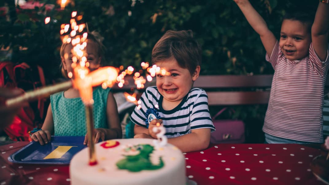 Kinder mit Geburtstagstorte mit Wunderkerze