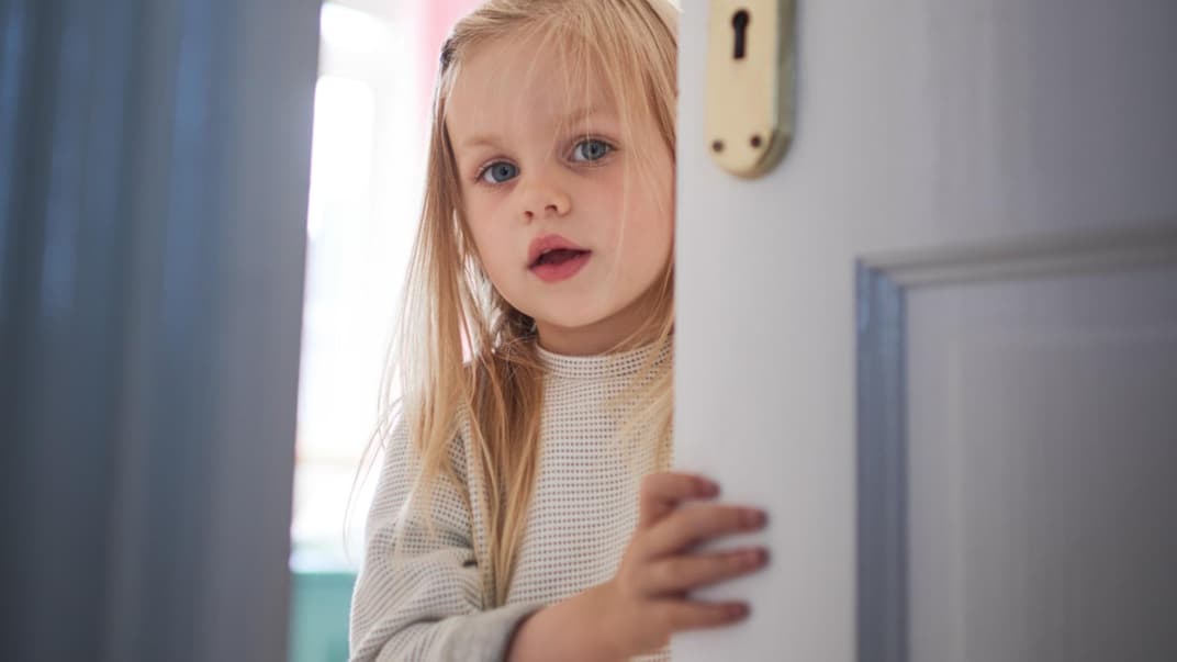 Kleines Kind schaut durch die Tür.