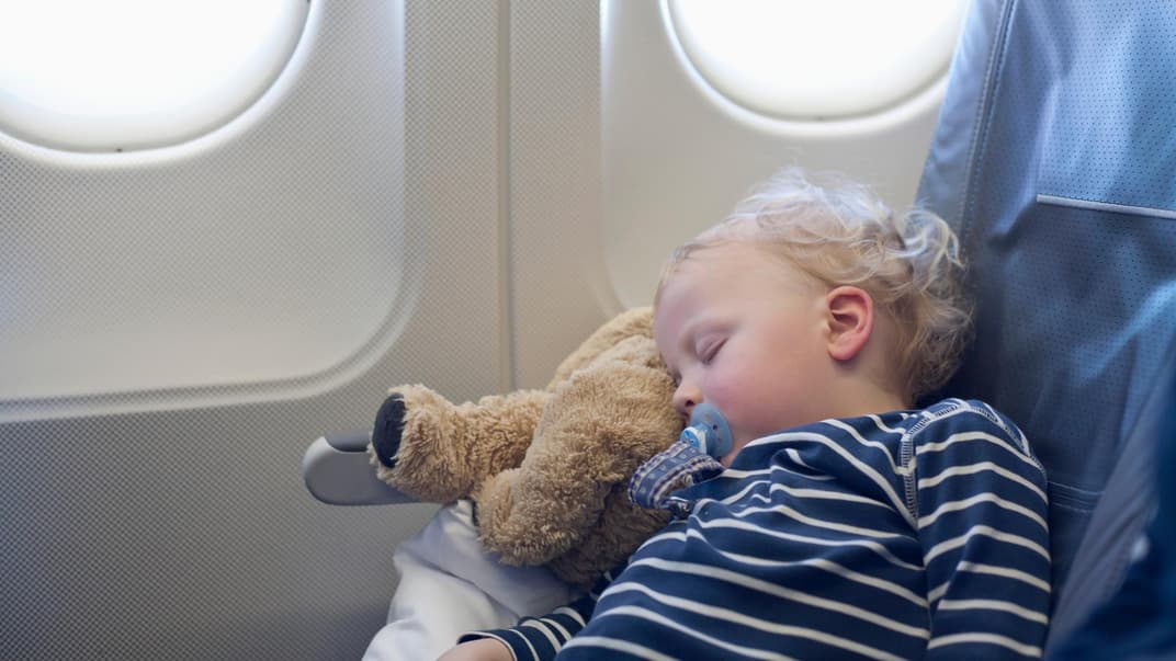 Ein kleiner Junge schläft im Flugzeug. 