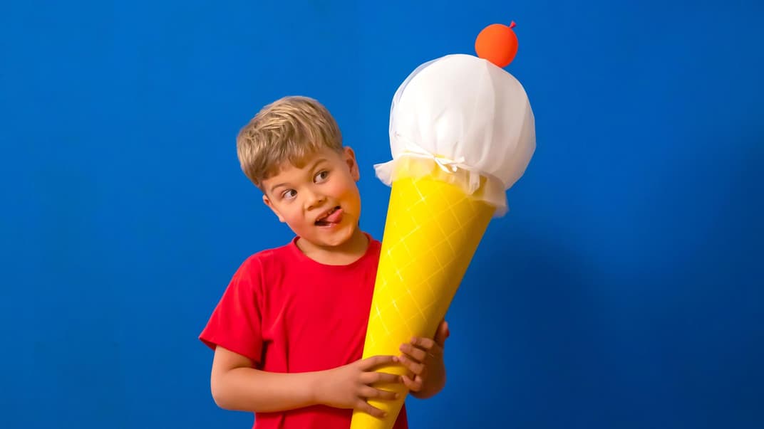 Ein kleiner Junge, der eine selbstgebastelte Eis-Schultüte in der Hand hält.