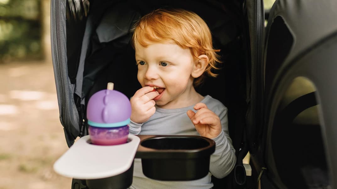 Kind snackt im Buggy.