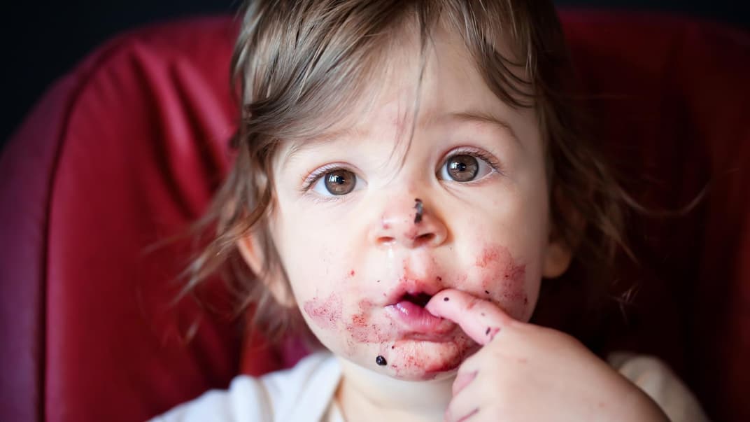 Kleines, niedliches Kind mit beerenverschmiertem Gesicht