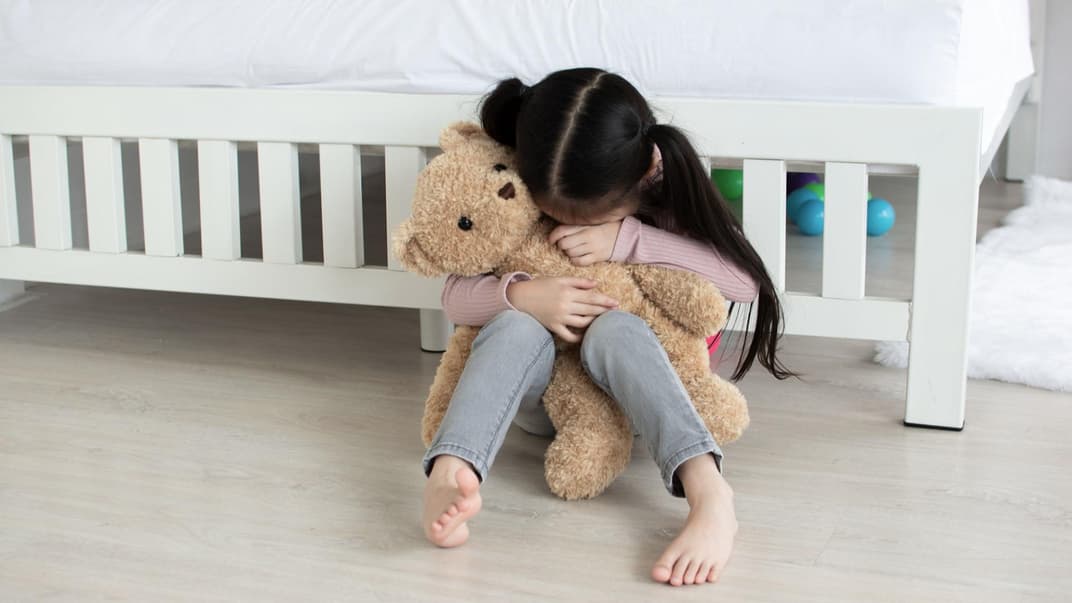 Kind hat Heimweh und weint in seinen Teddy.