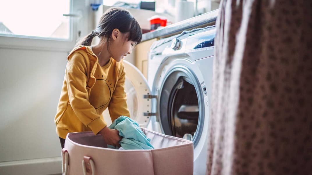 Kind befüllt die Waschmaschine.