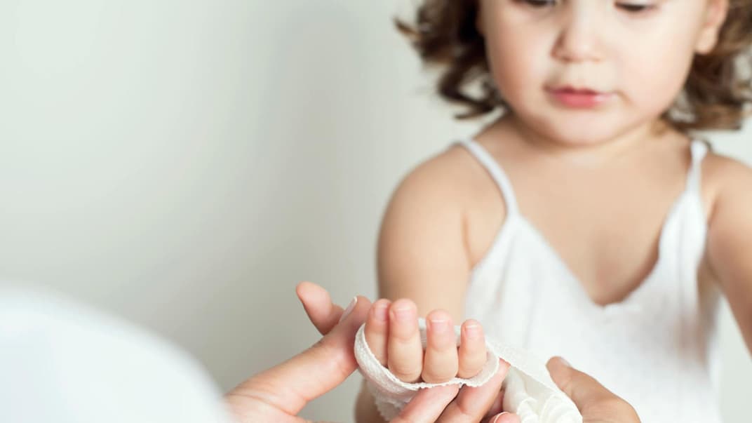 Kind bekommt einen Verband um die Hand.
