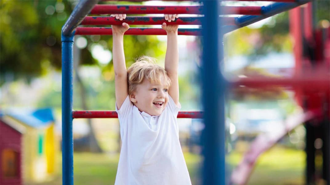 Kind hängt am Klettergerüst.