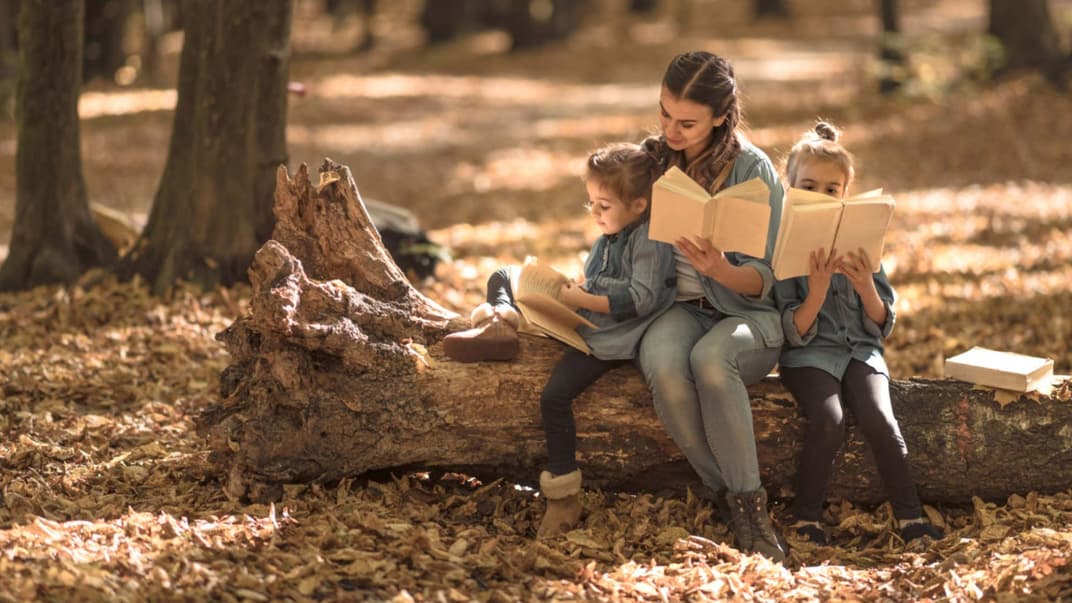 Eine Mutter übt mit ihren zwei Kindern Herbstgedichte.