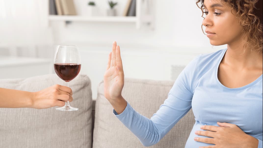 Schwangere Frau lehnt ein Glas Wein ab.