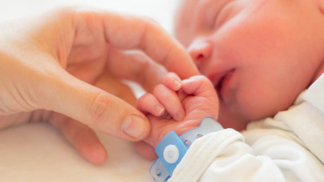Eine Mama streichelt die Hand ihres neugeborenen Babys