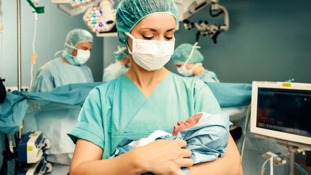 Schwester hält Neugeborenes im Arm.