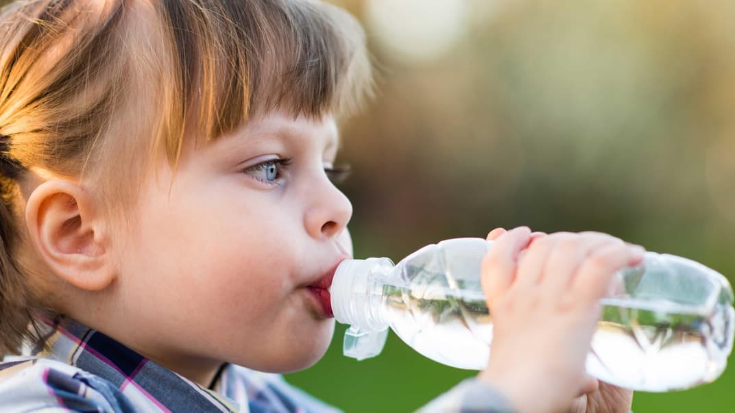Mädchen trinkt aus einer Wasserflasche.