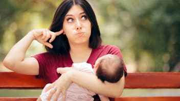 Mutter mit Baby im Arm hält sich die Ohren zu.