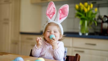 Ein kleines Mädchen lächelt und hat ein gefärbtes Osterei in der Hand.