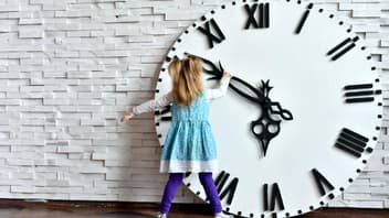 Kleines Mädchen steht vor riesiger Uhr