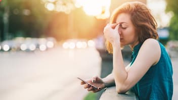 Frau gestresst mit Handy in der Hand
