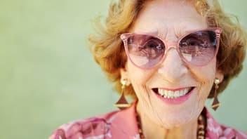 Lachende alte Frau mit rosa Sonnenbrille.