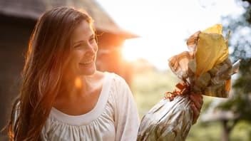Eine Frau bekommt ein Ostergeschenk überreicht und freut sich.