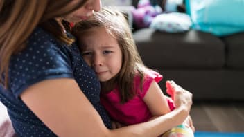 Mutter tröstet ihre kleine Tochter und hält sie im Arm.