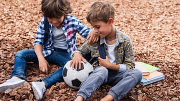 Zwei Jungen mit Fußball und Büchern.