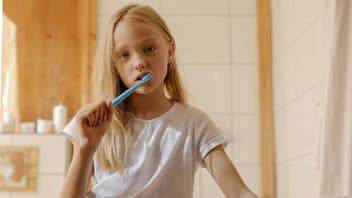 Ein Mädchen, das gelangweilt die Zähne putzt.