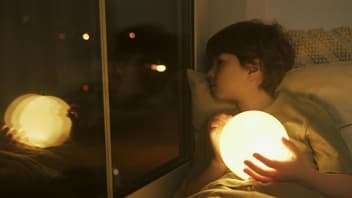 Ein Kind, das beim Einschlafen traurig aus dem Fenster guckt