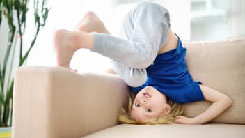 Junge macht Kopfstand auf dem Sofa.