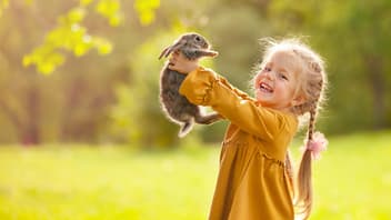 Mädchen hält Hasen hoch.