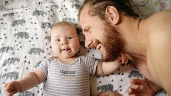 Ein Vater kuschelt mit seinem neugeborenen Baby.