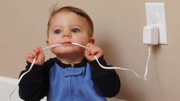 Ein Baby nimmt ein Ladekabel in den Mund. 