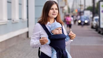Eine Mutter trägt ihr Baby mit Blick nach vorne in der Trage 